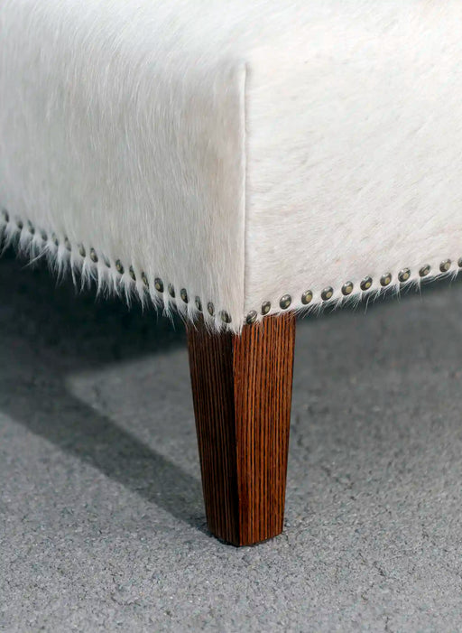 Wood stud and studs on a cowhide ottoman